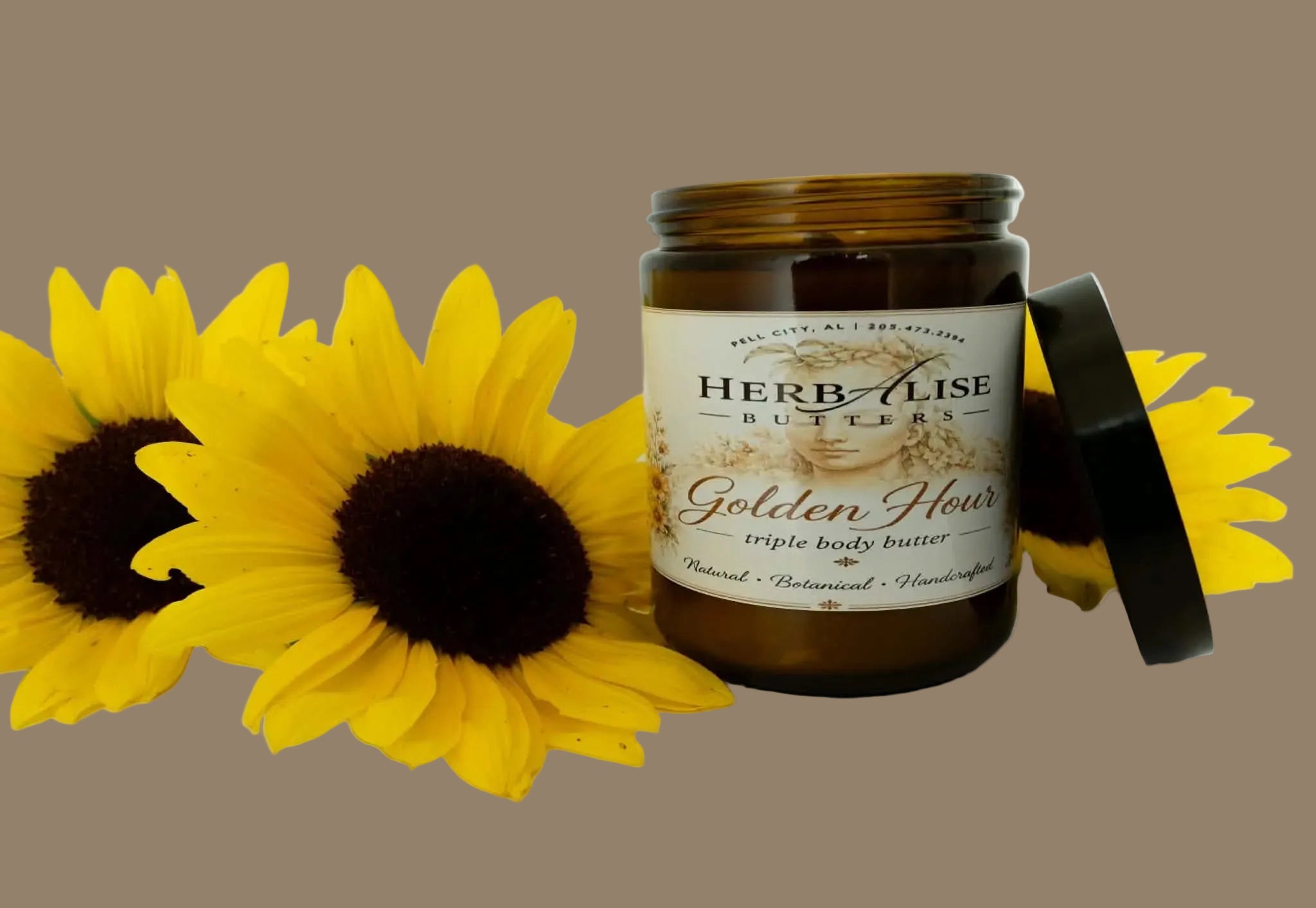 An amber glass jar of Herb Alzise Butters Golden Flour triple body butter with its black lid leaning against it, styled with three yellow sunflowers on a clean white background.