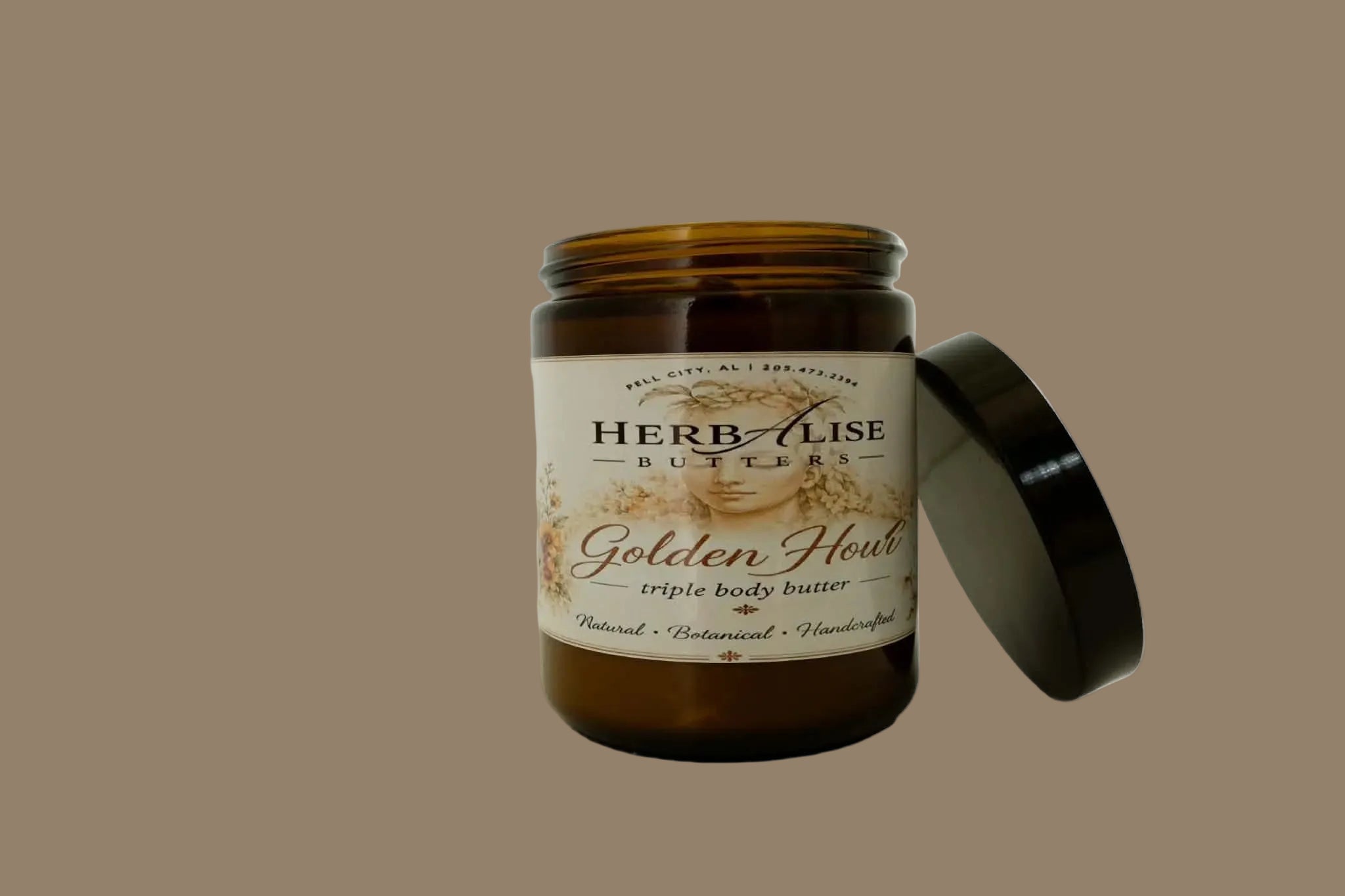 An amber glass jar of Herb-lise Butters 'Golden Hour' triple body butter with its black lid leaning against it on a plain white background.